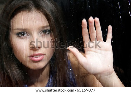 young girl behind wet window