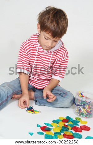 cute boy playing with colorful details studio shot