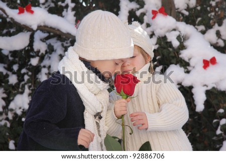 young boy and girl with red rose on natural winter background