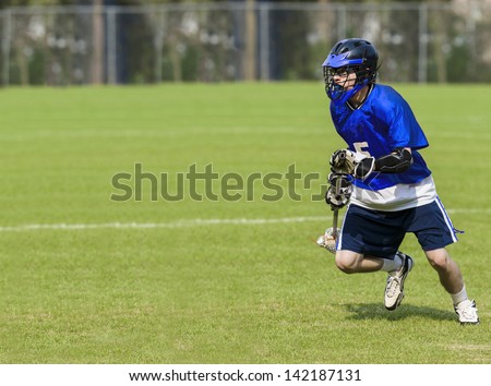 Male Lacrosse Player holding stick on a grass field with copy space