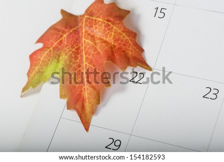 Colorful maple leaf on the calendar indicating the first day of fall or autumn with a shallow depth of field
