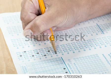 Close up of a hand holding a pencil taking a standardized test