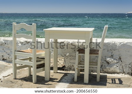 Off white table and chairs outside in front of gorgeous multicolored water background