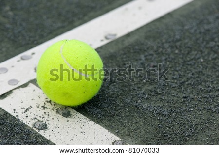 Yellow tennis ball in corner of the court