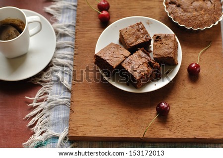Brownies on a wooden background with coffee and cherries