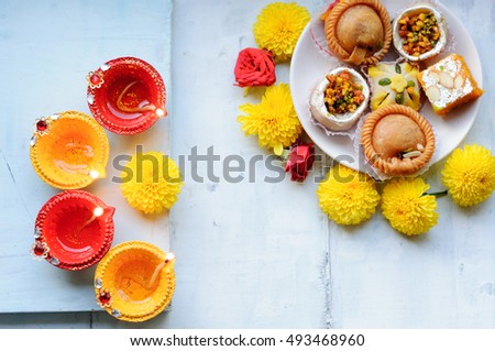 Set of yellow and red diyas on a blue background with flowers and sweets or mithai