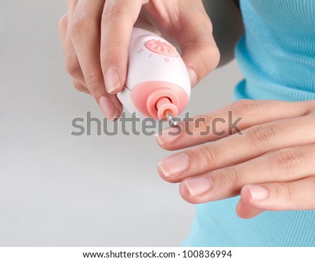 A woman polishing her fingernails by polish nail machine