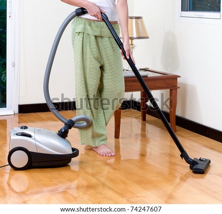 Housewife using vacuum cleaner machine to clean her house