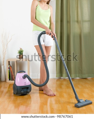 Housewife using vacuum cleaner machine to clean the floor