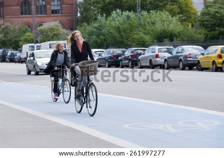 COPENHAGEN, DENMARK - August 5: Unidentified woman drives her bicycle in traffic during a work day. On August 5,2014.