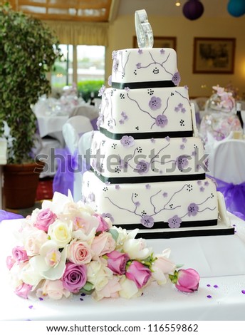 Purple wedding cake with brides bouquet at reception