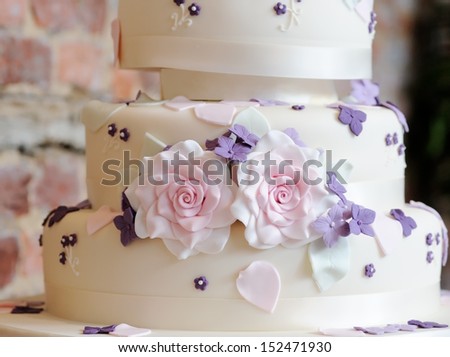 Wedding cake closeup with pink and purple flowers decorating at reception