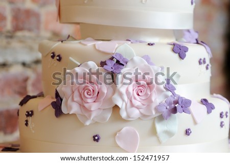 Closeup wedding cake decoration of pink and purple flowers at reception