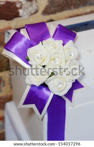 Wedding reception closeup detail of decoration is purple ribbon in a bow and white flowers