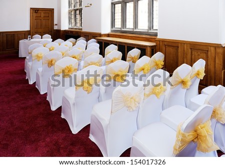 Wedding ceremony furniture and chairs with white covers and yellow ribbon