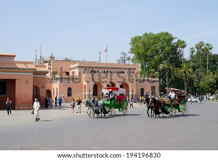 MARRAKESH, MOROCCO - MAY 9: Horse and carriages carrying customers and tourists near to landmark of mosque near market square . Marrakesh, Morocco May 9, 2014