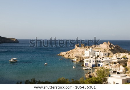 fisherman houses built into rock cliffs on Mediterranean Sea Firopotamos harbor Milos Cyclades Greek Island Greece with Greek church