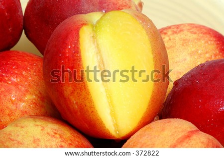 one sliced peach in a bowl with more peaches