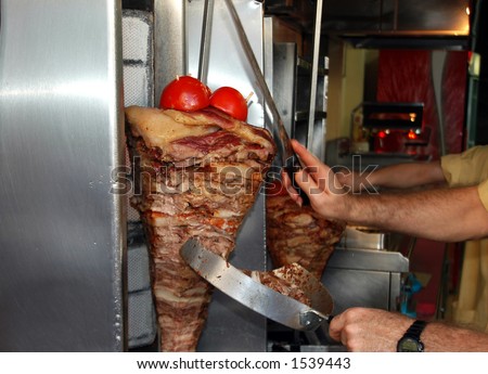 meat for gyro roasting on spit greece as chef slices meat photographed in athens greece