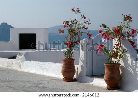 santorini greek islands stone patio with geraniums and sailboat in sea
