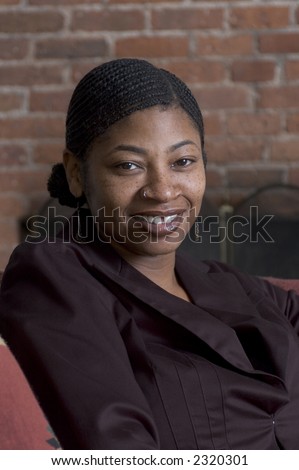 beautiful black woman smiling on sofa with fireplace