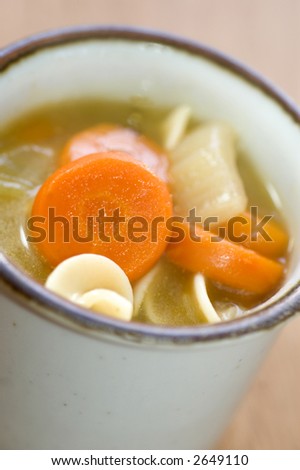 turkey noodle soup with carrots in bowl macro