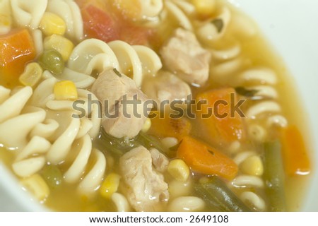 turkey chicken corn noodle soup with carrots in bowl macro wood background