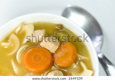 turkey noodle soup with carrots in bowl macro wood background