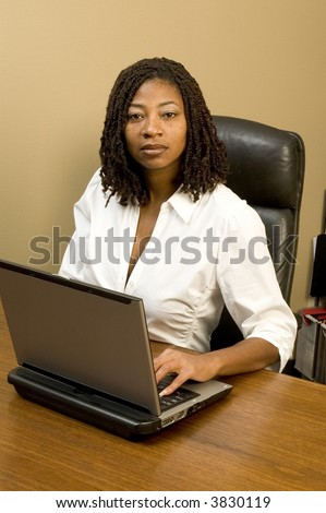 attractive black woman in office working computer braided hair