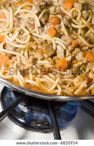 spaghetti bolognese cooking in pan on a stove range at home