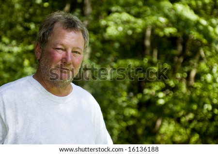 happy smiling baby-boomer middle age man wooded backyard background unshaven with beard stubble