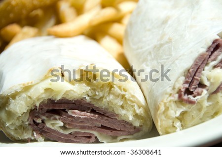 thick corn beef reuben wrap sandwich with swiss cheese sauerkraut and french fries potatoes