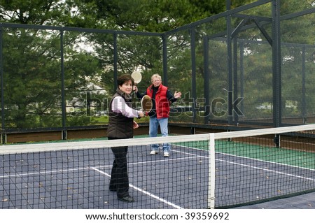platform tennis game played by middle age retired senior man and woman on suburban paddle court