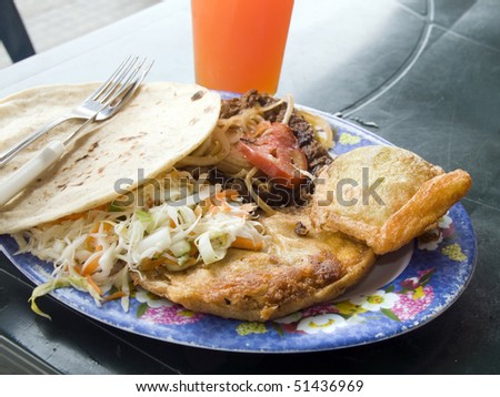 plate of mixed typical street vendor food empanadas beef salad taco and fresh papaya juice photographed in leon nicaragua