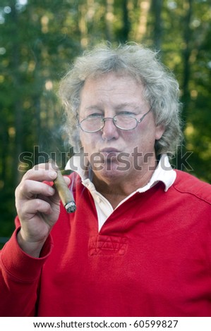 senior man with long hair smoking large cigar with selective focus on cigar