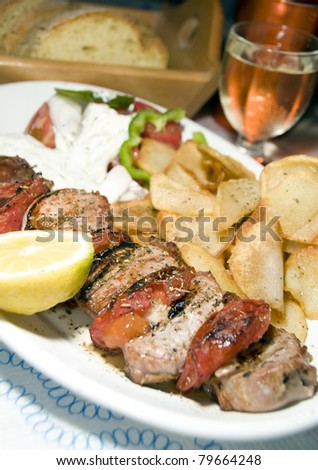 Pork souvlaki on skewer with tzatziki salad fried potatoes house wine crusty Greek bread as photographed in taverna restaurant Cyclades Greek island Greece