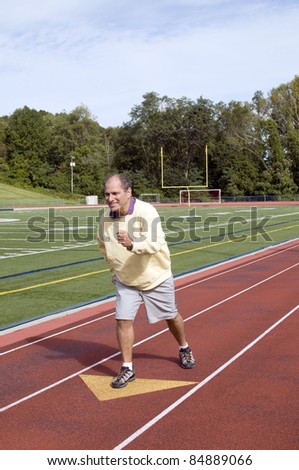 handsome middle age senior man stretching exercising running jogging on sports football field and running track