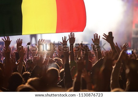 football supporters with raised hands against Belgium flag - crowd in stadium celebrating victory