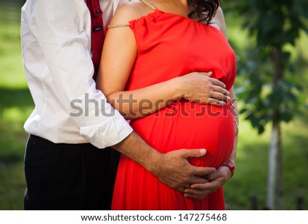 Image of pregnant woman and father embracing touching her belly with hands