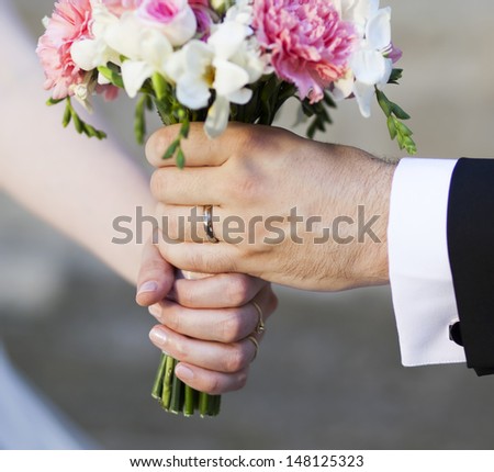 Groom handing over wedding bouquet - focus on rings