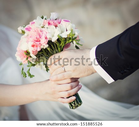Groom handing wedding bouquet to bride