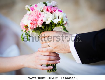 Groom handing wedding bouquet to bride