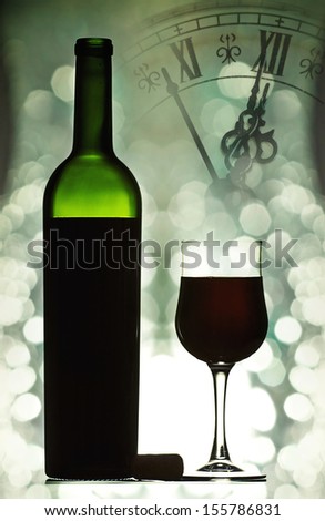Red wine against holiday lights and clock close to midnight