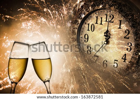 Champagne glasses, clock and fireworks at midnight