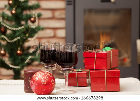 Red gift boxes in front of Christmas tree and fire burning in fireplace