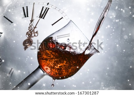 Red wine against fireworks, holiday lights and clock close to midnight