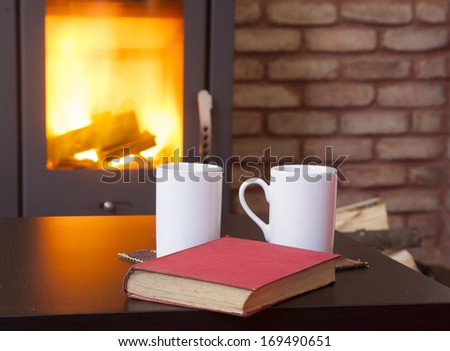 Home interior with fireplace, red book and tea on table