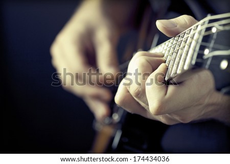 Close up on hands playing on electric guitar