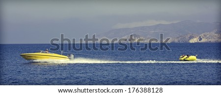Jet ski and two kids trying not to fall off a water tube