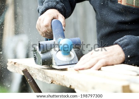 Man\'s arms sawing wood board in the workshop.